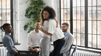 Smiling diverse multiethnic people hug support each other at psychological meeting indoors. Happy...