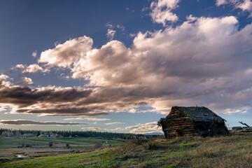 Rustic weathered log cabin with dramatic evening sky