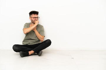 Young caucasian man sitting on the floor isolated on white background is suffering with cough and feeling bad