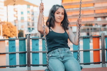 Adolescente balanceandose en el columpio del parque columpiandose con una sonrisa