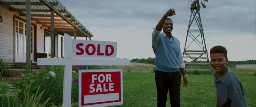 Portrait of Happy African American father teasing family with keys from their new house. Shot with 2x anamorphic lens