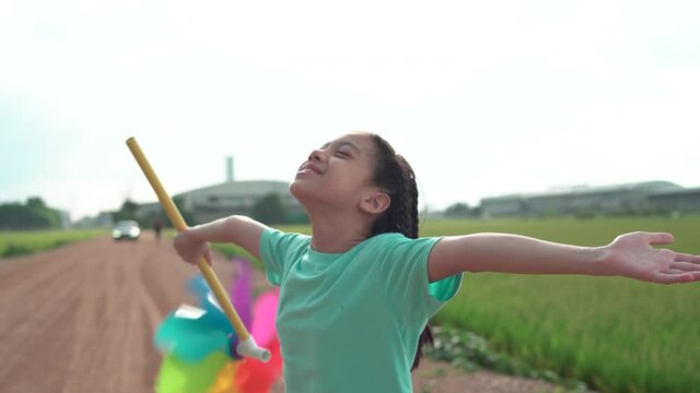 Asian child girl with pinwheels enjoying freedom with open hands, Happy kid playing outdoor