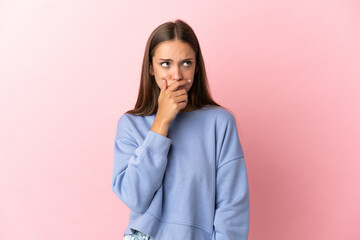 Young woman over isolated pink background having doubts and with confuse face expression