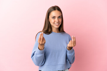 Young woman over isolated pink background making money gesture