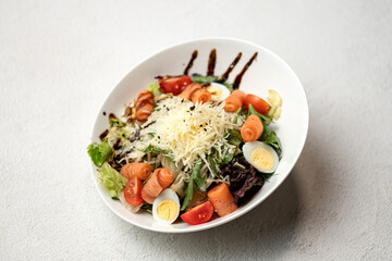 Caesar salad with red fish and grated Parmesan cheese. Food plate on white background. Horizontal format.
