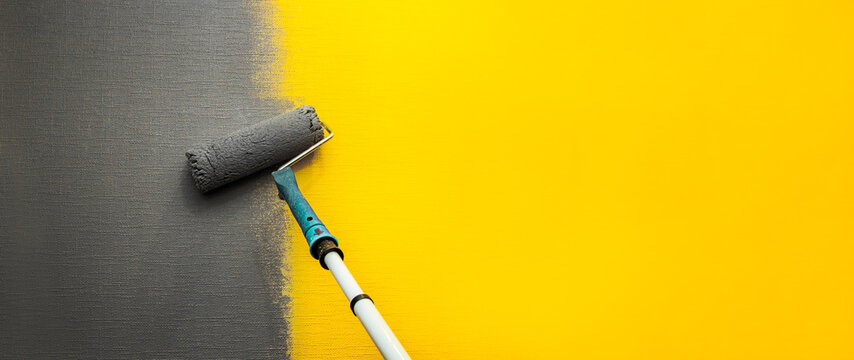 Close up roller with gray paint for painting walls. Repairs. Yellow wall. Background. Screensaver for the site. High quality photo
