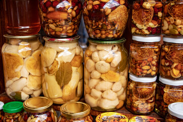 Glass jar of preserved many mushroom and nuts with honey in glass jars.