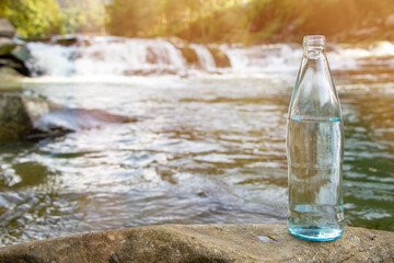 Natural drinking water in a bottle on nature background river