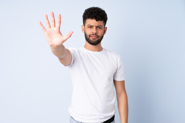 Young Moroccan man isolated on blue background counting five with fingers