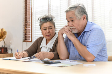 Obraz premium Portrait photo of senior Asian couple feeling sad or worry about their financial situation because too many daily expense. Senior couple consulting and discussing about family expenditure.