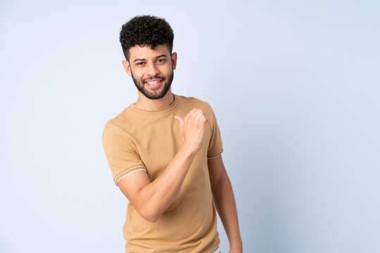 Young Moroccan man isolated on blue background proud and self-satisfied
