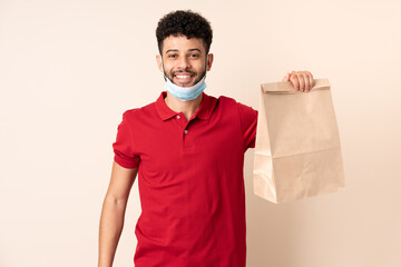 Young man holding a takeaway food bag ___ smiling a lot