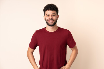 Young Moroccan man isolated on beige background laughing