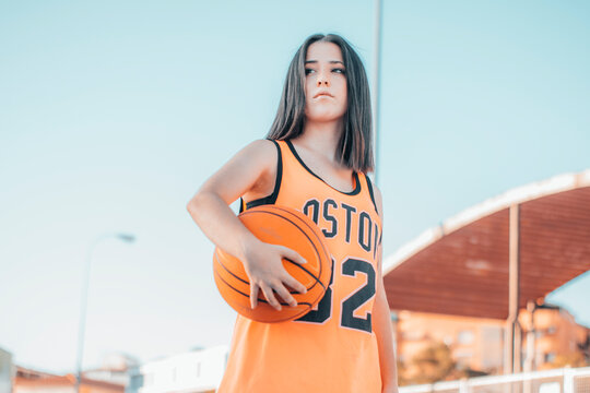 Ni&ntilde;a Deportista y joven jugando al baloncesto con una pelota en una pista de juego para encestar el balon en la canasta