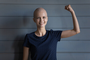 Happy strong cancer survivor beating disease, winning fight for life. Young woman with shaved head...