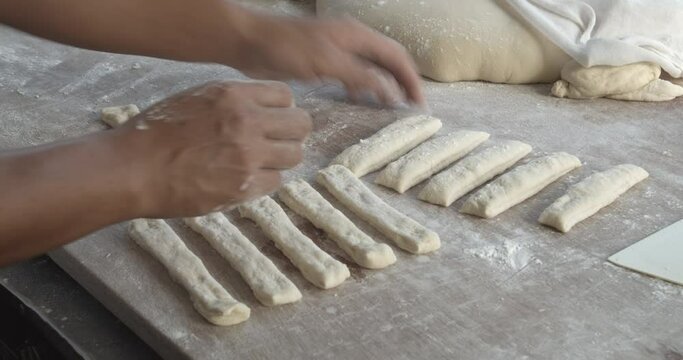 handheld 4K 25fps video of Chef is shaping dough sticks prepare to fry in hot oil.Youtiao is a hugely popular Chinese street food, a deep-fried breadstick crispy outside with a spongy interior.