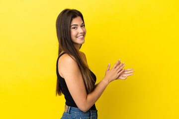 Young Brazilian woman isolated on yellow background applauding