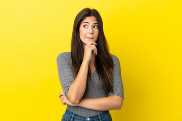 Young Brazilian woman isolated on yellow background having doubts and thinking