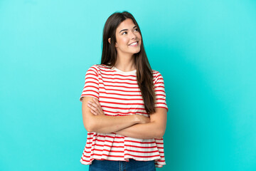Young Brazilian woman isolated on blue background looking up while smiling
