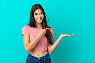 Young Brazilian woman isolated on blue background holding copyspace imaginary on the palm to insert...