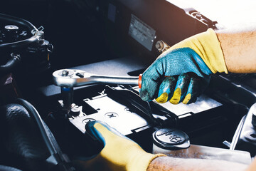 The Mechanic hand is fasten the bolt of battery Anode with socket wrench