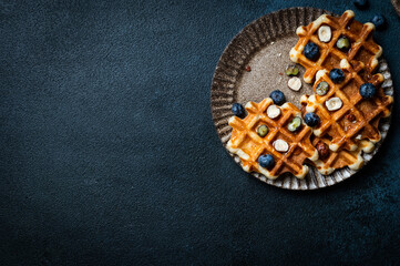 Freshly made belgian waffles with blueberry and hazelnut. Waffles with honey and berry. Place for...