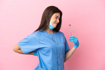 Dentist woman holding tools isolated on pink background suffering from backache for having made an effort