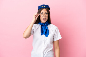 Airplane stewardess Brazilian woman isolated on pink background with glasses and surprised