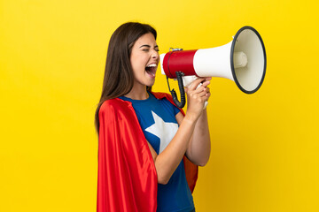 Super Hero Brazilian woman isolated on yellow background shouting through a megaphone