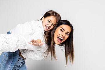 Mother giving her daughter piggyback ride against white background