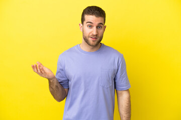 Handsome blonde man over isolated yellow background making doubts gesture