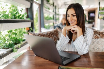 Young pretty woman working with laptop in cafe