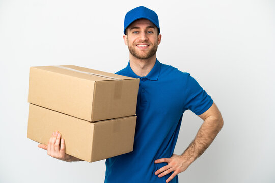 Delivery man over isolated white background posing with arms at hip and smiling