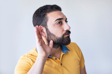 Man isolated on gray background pressing hand to ear trying to hear something better