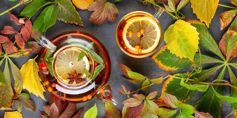 Autumn warming tea with lemon, sea buckthorn and rosehips in a glass teapot on the table. Top view.