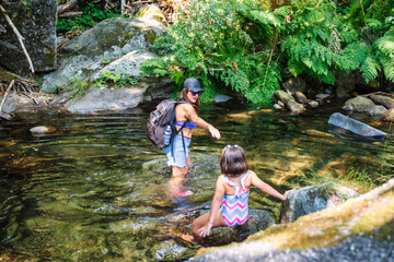 Mother And Daughter Enjoying An Excursion In A Forest And Are Walking Along A River. Woman And...