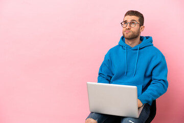 Young man sitting on a chair with laptop and looking up