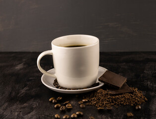 a cup of black invigorating coffee with chocolate bars and grains