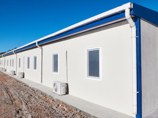 Fototapeta na wymiar Mobile industrial building. Newly built single storey prefabricated industrial building. Prefabricated office container building at construction site