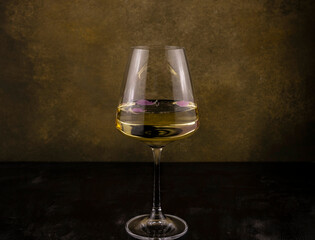 a glass of white wine with rose petals in it