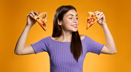 Happy smiling girl holding two slices of pizza, choosing what to eat, standing against orange background. Concept of pizzeria fast food, eating out and delivery - obrazy, fototapety, plakaty