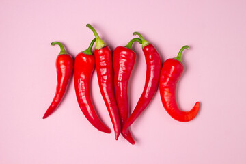 Red hot chili peppers on a pink background. Isolated hot peppers