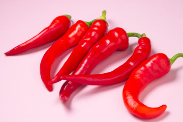 Red hot chili peppers on a pink background. Isolated hot peppers