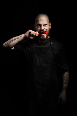 Portrait of chef biting spicy red pepper