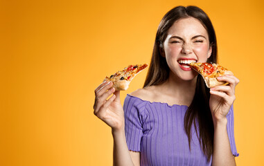 Image of brunette girl eating pizza with satisfaction, laughing, biting slices and looking pleased...