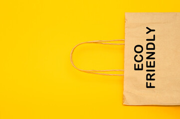 Paper recyclable eco friendly shopping bag on yellow background, top view copy space.
