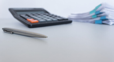 Stack of documents , calculator, pen placed on a business desk in a business office. Copy space