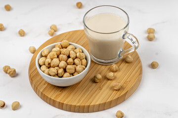 Hazelnut milk in a glass with nuts on a wooden table