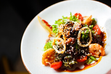 sea salad with mussels and squid in a white plate on a dark background