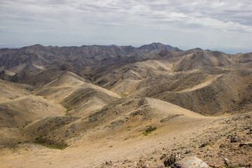 Beautiful Summer scenery: yellow and brown mountains under the blue cloudy sky. Central Asian mountain background. 